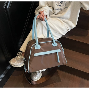 Detail of blue leather handles and detachable shoulder strap on nylon tote bag