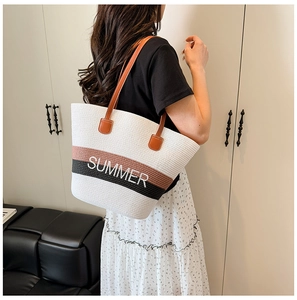 Detail of large straw tote bag with SUMMER lettering and brown leather straps