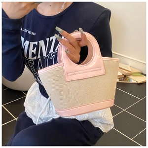 Detail of pink patent leather and beige woven tote bag with unique round cutout handle
