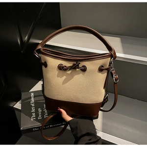 Detail of canvas bucket bag with leather trim, toggle closure and adjustable shoulder strap