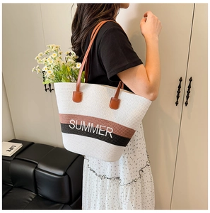 Detail of summer straw tote bag with contrast stripes and embroidered SUMMER text