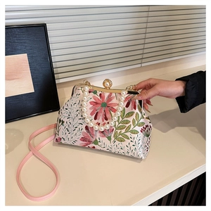 Close-up of floral embroidery pattern and large pearl handle on retro evening clutch bag