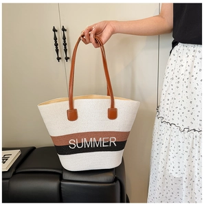 Close-up of woven straw tote bag with SUMMER embroidery and brown leather handles
