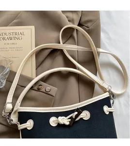 Detail of canvas crossbody bag with smooth long shoulder strap and leather trim accents