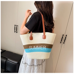 Close-up of SUMMER embroidery on a striped straw tote bag with brown leather straps