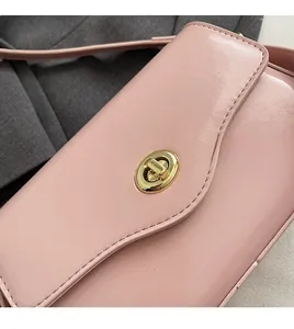 Gros plan d'un sac à rabat en cuir PU rose avec fermoir rotatif doré et texture lisse