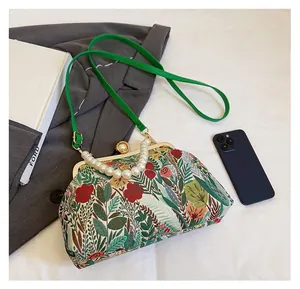 Detail of floral embroidery evening bag with pearl handle and green shoulder strap
