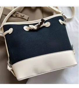 Detail of canvas bucket bag showing leather stitching, drawstring, and toggle closure