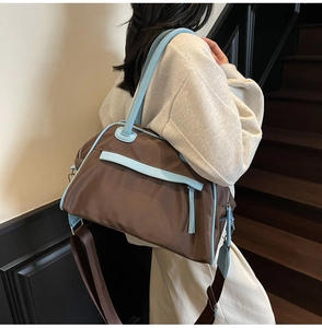 Detail of dark brown waterproof nylon tote bag with blue leather trim on a model