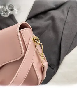 Gros plan du fermoir en métal doré et des coutures sur le sac bandoulière en cuir rose