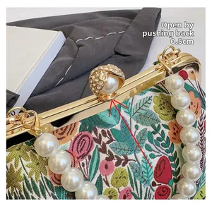 Macro detail of retro floral embroidered evening bag showing pearl clasp opening method