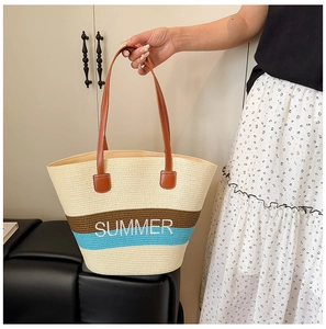 Close-up of beige woven straw tote bag with SUMMER embroidery and blue stripes