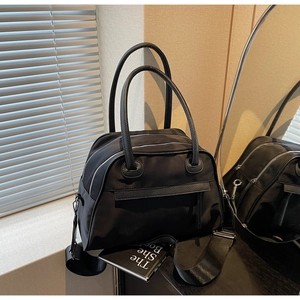 Detail of multi-compartment black nylon tote bag with wide shoulder strap and zippers