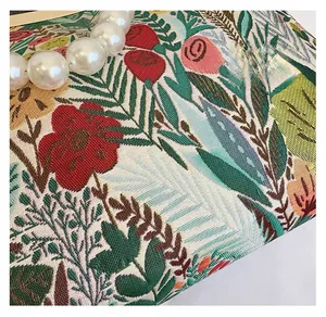 Detail of floral jacquard fabric evening bag with large pearl handle and gold metal clasp