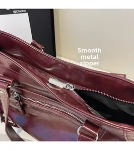 Dettaglio della cerniera in metallo argentato sulla borsa tote in pelle bordeaux liscia