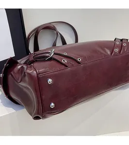 Dettaglio del fondo borsa in pelle bordeaux con quattro borchie protettive in metallo