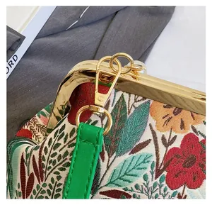 Detail of floral embroidery fabric and detachable green strap with gold metal hooks
