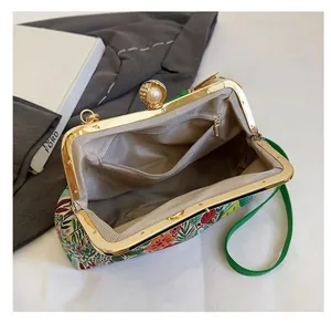 Detail of floral evening bag with pearl clasp, green leather strap, and inner zip pocket