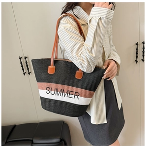Detail of large woven straw tote bag featuring Summer embroidery and leather straps