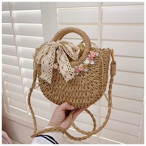 Detail of straw woven bucket bag featuring lace bow and delicate floral embroidery decorations