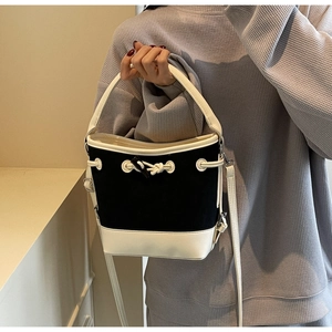 Detail of canvas bucket bag with contrast leather trim, knot accent and metal rings