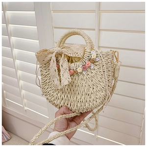 Detail of straw woven handbag with large lace bow and colorful floral decorations