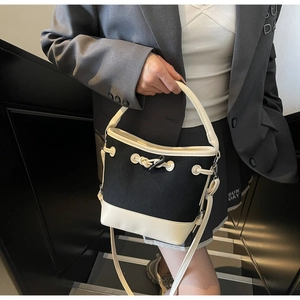 Detail of canvas bucket bag showing black and white contrast stitching and drawstring closure