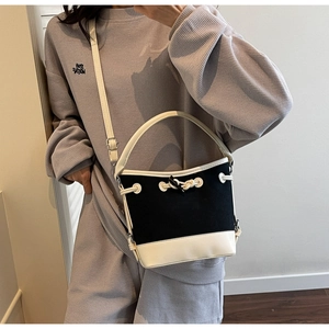 Detail of contrast canvas bucket bag with black body, white leather trim and knot decor