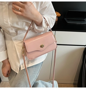Détail du sac bandoulière rose clair avec fermoir doré et rabat ondulé sur fond minimaliste