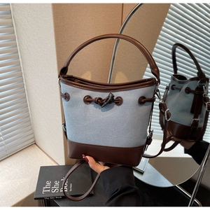 Detailed shot of retro canvas bucket bag with brown leather trim and drawstring closure