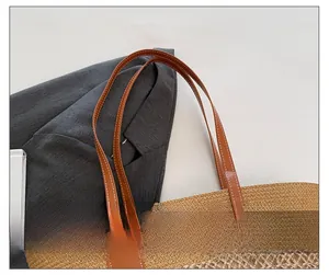 Detail of the brown faux leather strap stitching on a beige straw tote beach bag