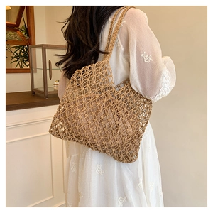 Detail of hand-woven hollow mesh tote bag in light brown showing texture and drape