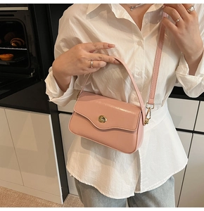 Détail d'un sac bandoulière rose clair avec rabat ondulé et fermoir rotatif doré