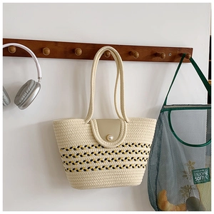 Detail der geflochtenen Strohtasche mit geometrischen Streifen und Perlenverschluss