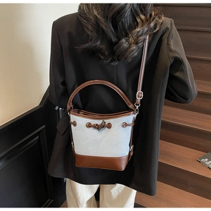 Lifestyle shot of a canvas bucket bag with brown leather trim and adjustable shoulder strap
