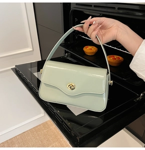 Détail d'un sac à main en cuir verni vert pistache avec fermoir doré rotatif élégant