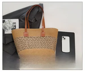 Detail showing hollow weave texture and brown leather handle of the straw tote bag