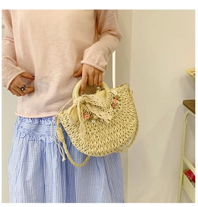 Detail of straw bag with lace bow and floral accents worn by a model in casual style