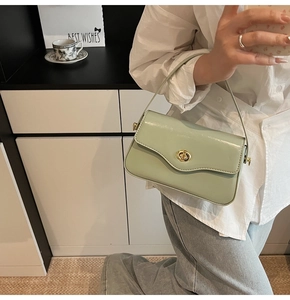 Détail du sac à bandoulière en cuir vert clair avec fermoir rotatif doré et rabat