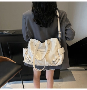 Dettaglio della borsa tote crema con tracolla regolabile indossata da una modella