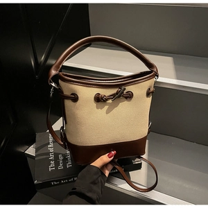 Detail of canvas bucket bag with brown leather trim and knot detail on steps