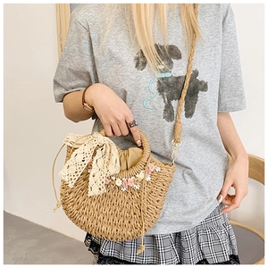Detail of hand-woven straw bag with lace bow, floral accents and drawstring lining