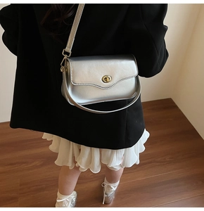 Détail du sac bandoulière argenté avec boucle dorée ronde et fini métallique lisse