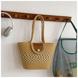 Detail einer Strohtasche mit Perlenverschluss und gestreiften dekorativen Gurtellementen