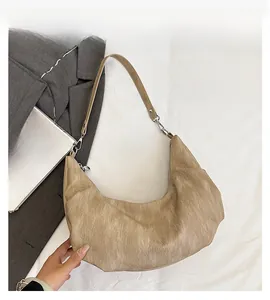 Detail of light brown crescent shoulder bag featuring fine pleated texture and slim strap