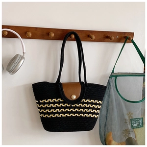 Detail der handgewebten Stroh-Tasche in Schwarz und Gelb mit Lederklappe und Perlenverschluss