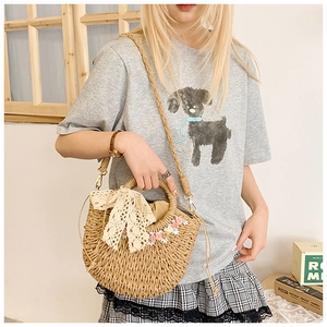 Detailed macro view of woven straw handbag featuring lace bow and floral appliques