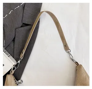 Detail of detachable beige faux leather strap with silver hardware on a crossbody bag