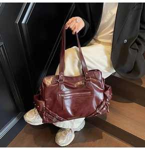 Dettaglio borsa tote bordeaux con borchie punk, cerniere e texture in pelle lucida