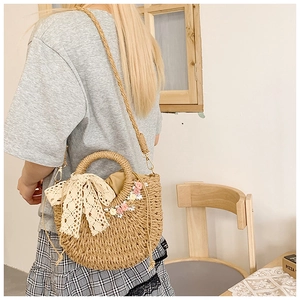 Detail of straw woven crossbody bag with floral embroidery and lace bow decoration